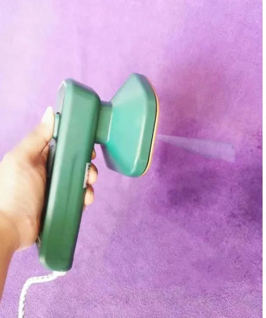 Dark green portable hand-held hanging steam ironing machine with a ceramic panel, shown with a power plug.