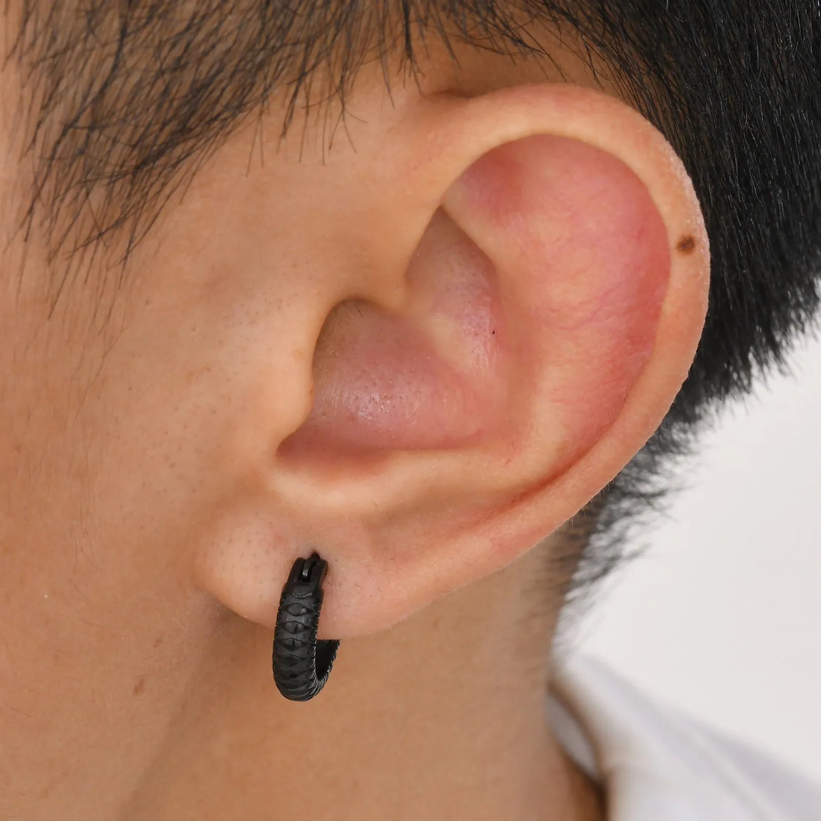 A pair of stainless steel hip hop earrings with a raised snake pattern, shown in black and gold colour options.