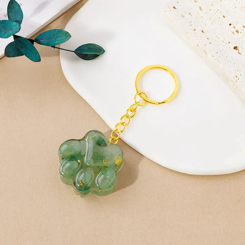 Natural crystal cat's paw shaped keychain charm on a keyring, showing colour variations of different gemstones.