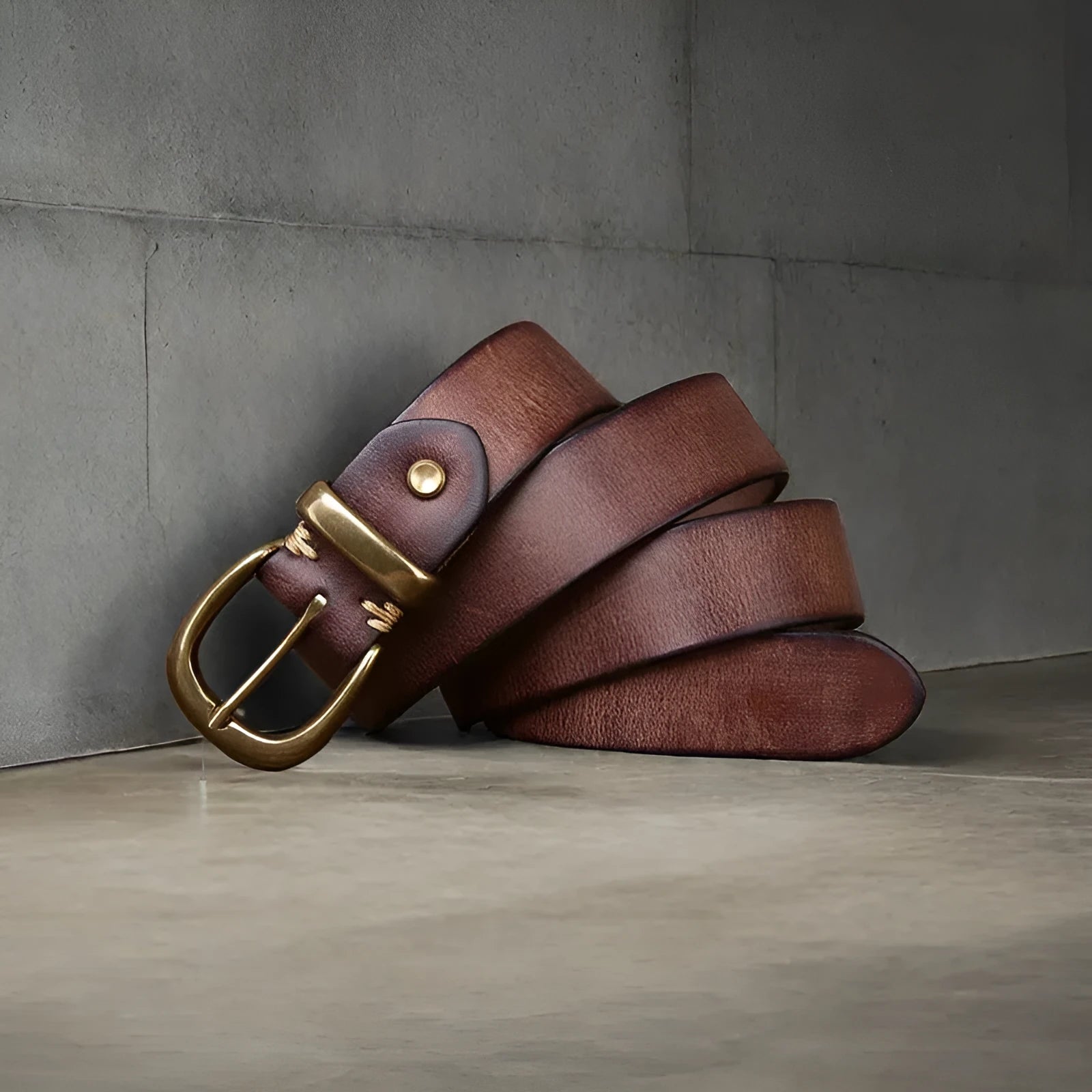 Men's brown casual leather belt with copper pin buckle on a jeans background.