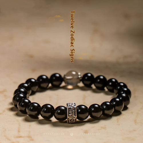 Dark 8mm obsidian bracelet with carved Chinese zodiac animal design on a wrist.