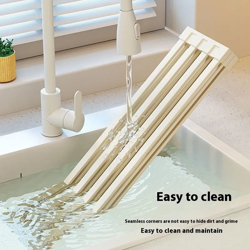 Milky white foldable stainless steel kitchen draining rack next to a sink.