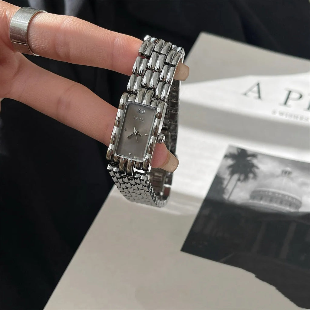Women's bracelet-style watch with 15mm dial, silver stripe strap, and butterfly clasp