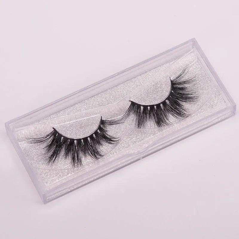 A pair of handmade 5D false eyelashes made from mink hair, shown with a double-headed brush and a hair cap.