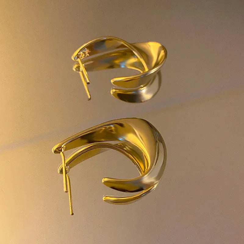 Twisted geometric metal earrings with electroplated gold finish and round design elements