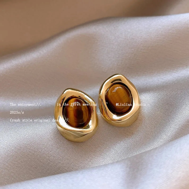 Handmade geometric earring set showing three styles: round piece, irregular amber, and water drop tigereye studs with tassels.
