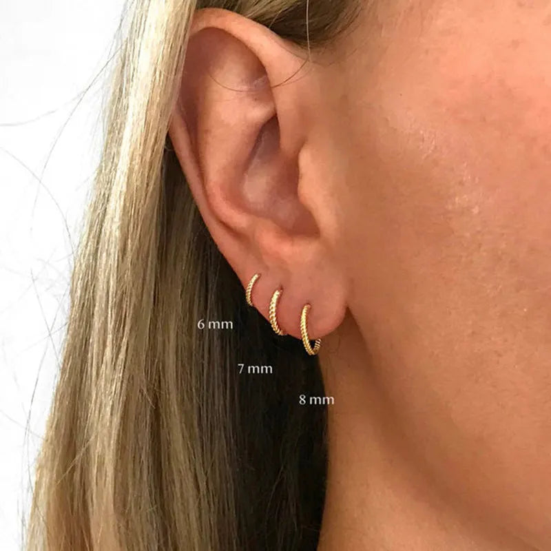 A pair of twisted sterling silver round earrings in a geometric design on a white background.