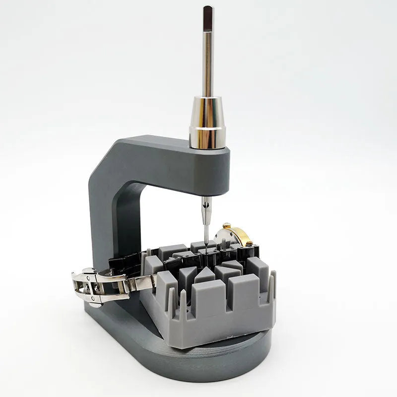 Silver coloured tool steel press strap removal tool for watch and jewellery repair on a dark surface.