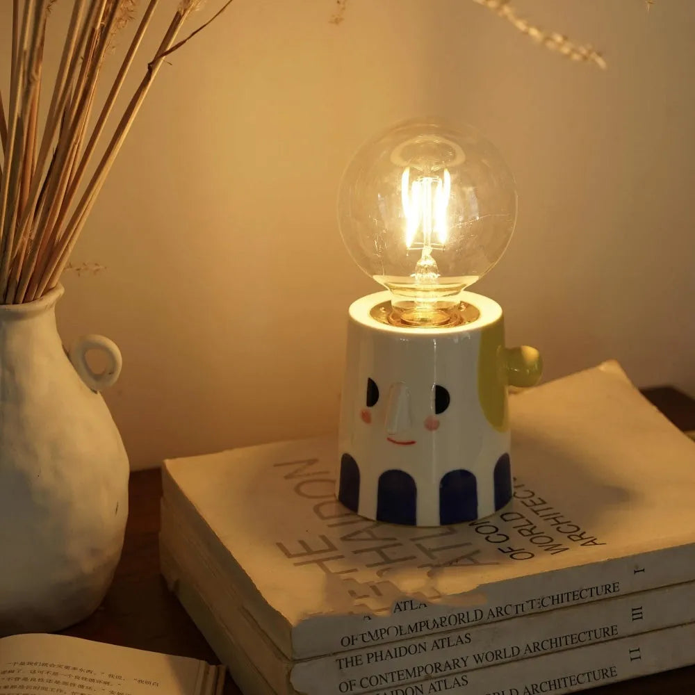 Handmade ceramic bedside lamp with a ball headlight design on a table.