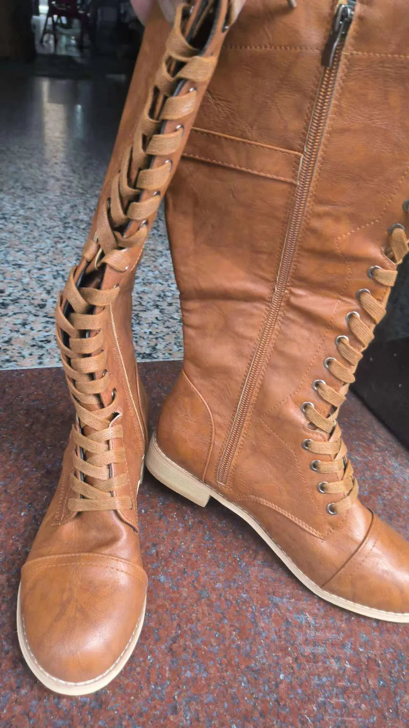Women's black cross strap knight boots made from PU leather, showing the knee-high design and strap detail.
