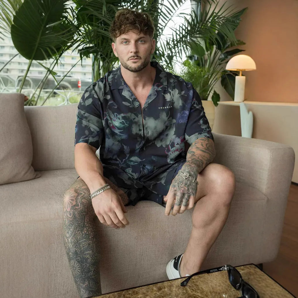 A man's loose-fitting, short-sleeve casual top with a floral print, shown in a light colour.