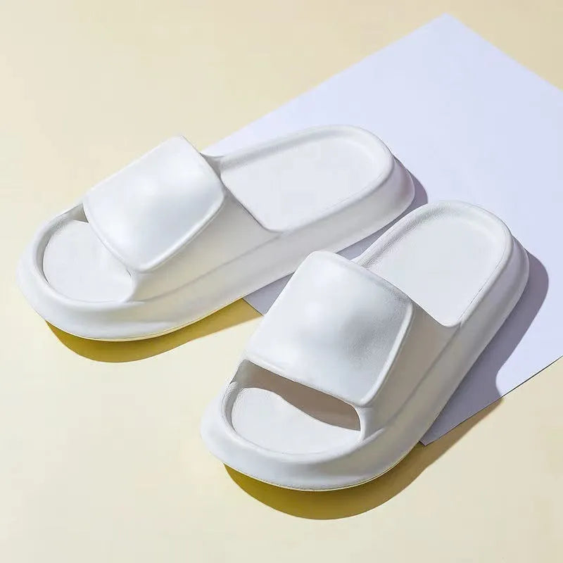 Pair of thick-soled white EVA foam flip-flop slippers on a bathroom floor, showing non-slip tread pattern.