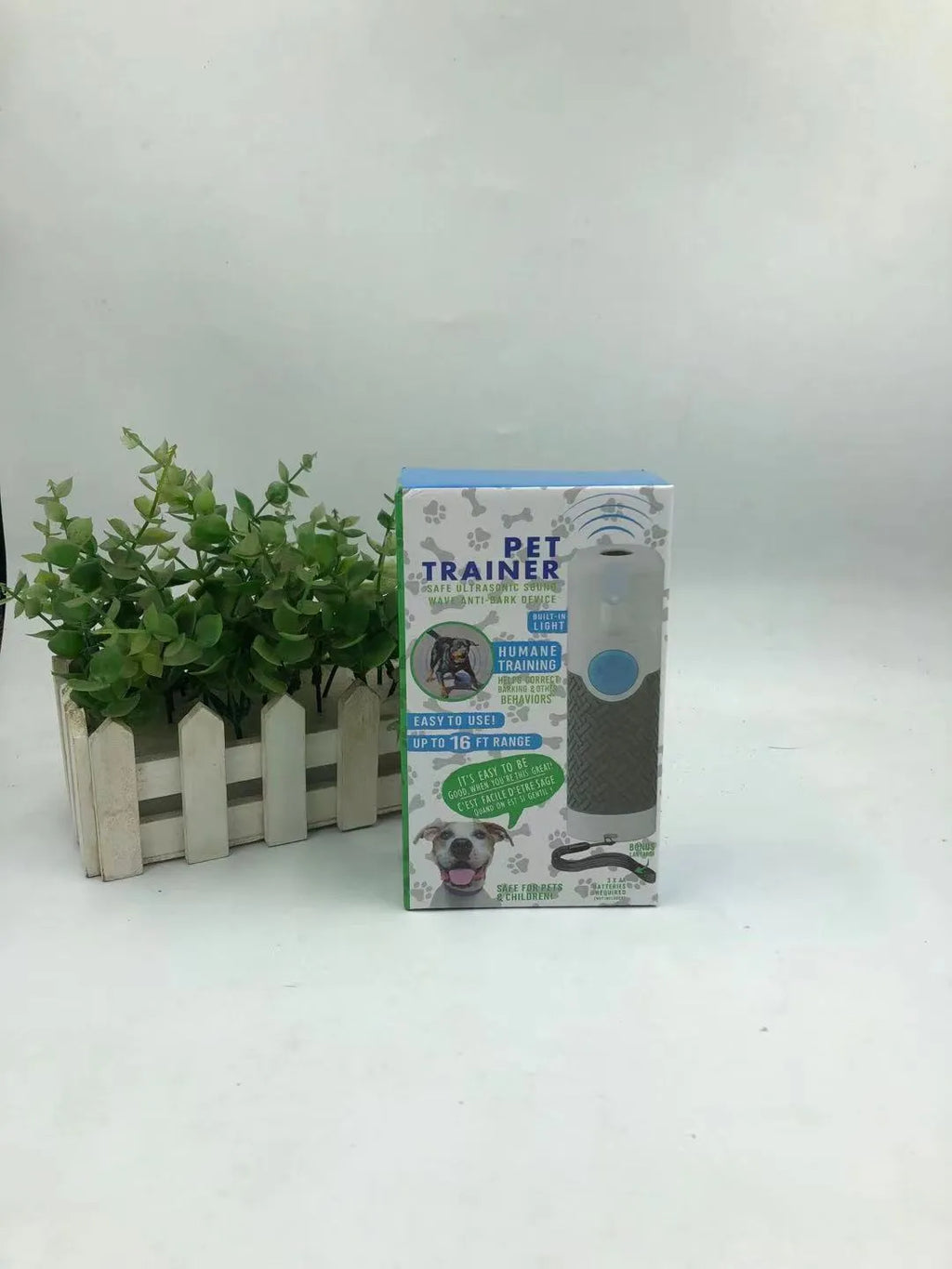 White handheld ultrasonic dog bark control trainer on a plain background