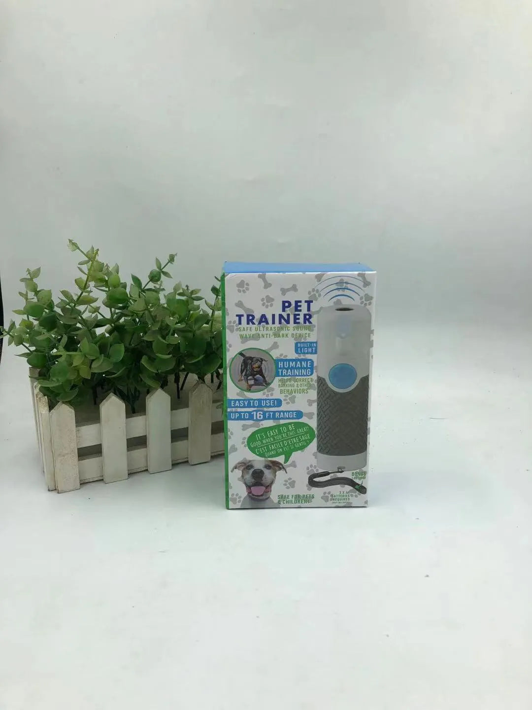 White handheld ultrasonic dog bark control trainer on a plain background