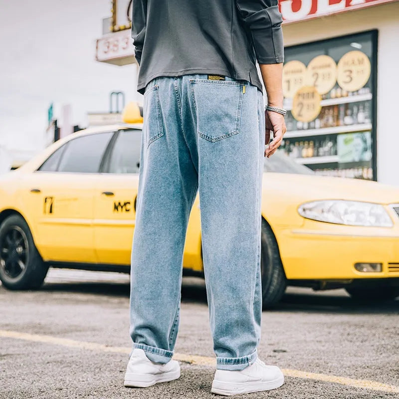 Man wearing loose straight-leg casual jeans in dark blue cotton fabric.