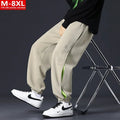 Man wearing loose grey-green cotton trousers with banded ankles and stitching detail.