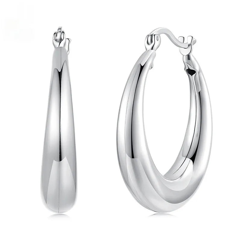 A pair of copper ring-shaped ear clip earrings with silver posts on a white background.