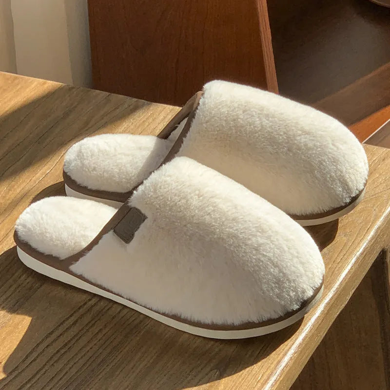 A pair of solid colour plush winter slippers with a non-slip PVC sole and car stitching detail.
