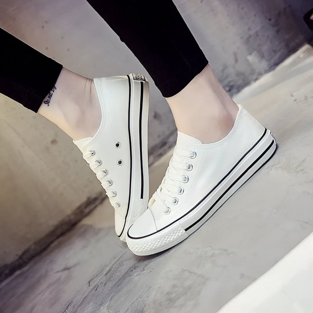Women's solid colour canvas slip-on shoes in black, white, and red variations on a plain background.