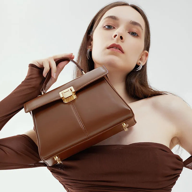 Women's black genuine leather shoulder bag with gold clasp closure showing interior compartments
