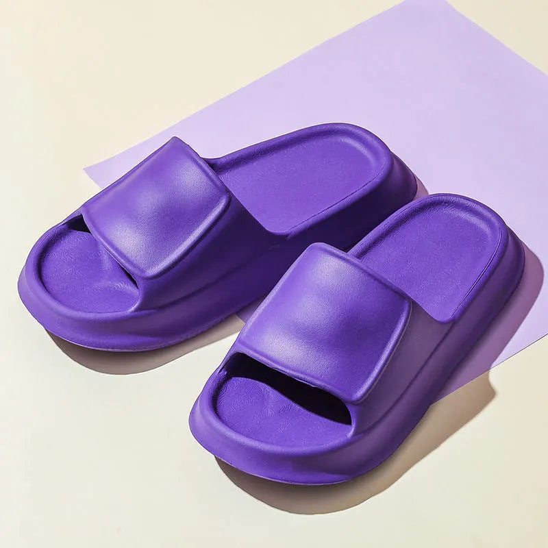 Pair of thick-soled white EVA foam flip-flop slippers on a bathroom floor, showing non-slip tread pattern.