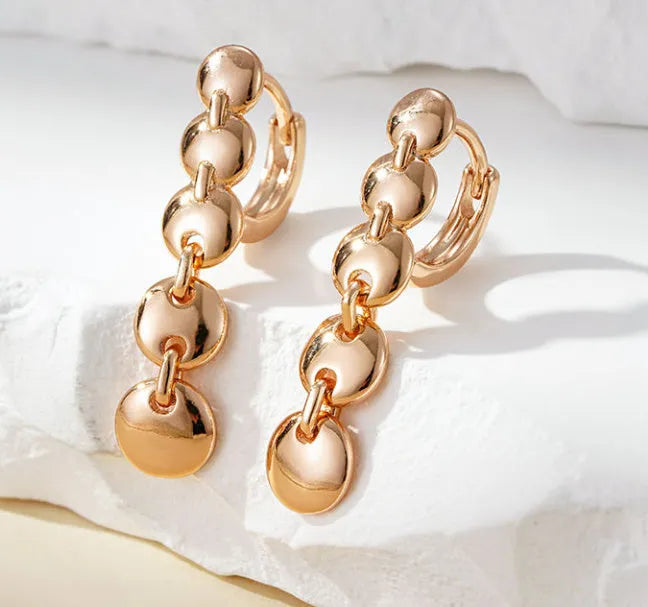 A pair of long gold-colour retro earrings with a woven round circle design made from copper.