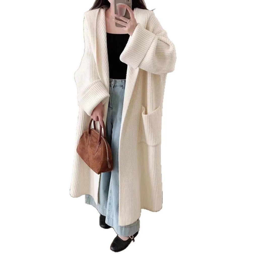 A long, loose grey hooded cardigan coat for women on a hanger, showing its length and raglan sleeves.