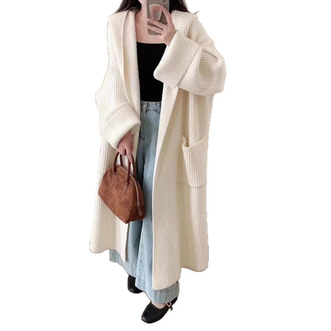 A long, loose grey hooded cardigan coat for women on a hanger, showing its length and raglan sleeves.