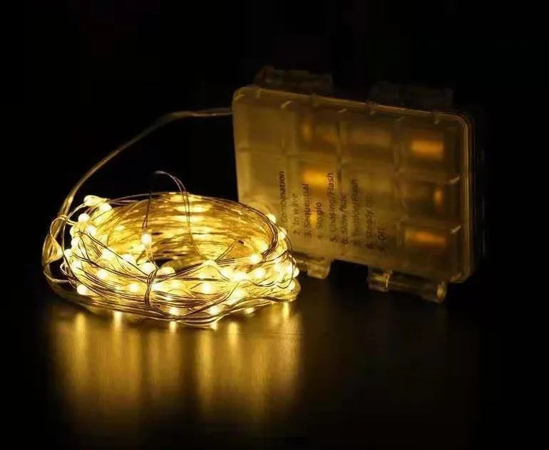 Copper wire LED string lights shaped around a bottle, showing multiple small coloured bulbs.