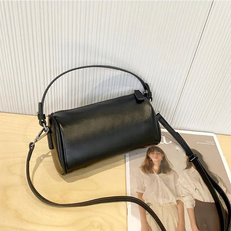 Soft genuine leather cylindrical crossbody bag in street style, shown in black, with a single strap.