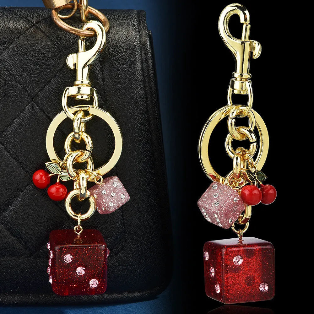 Square cherry two-tone dice keychain pendant on a metal ring.