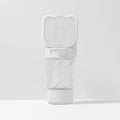 Green 3-in-1 pet water bottle with food container top and waste bag dispenser base, held by hand strap.