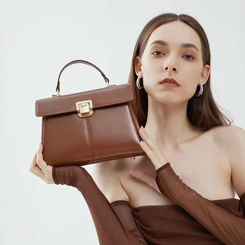 Women's black genuine leather shoulder bag with gold clasp closure showing interior compartments