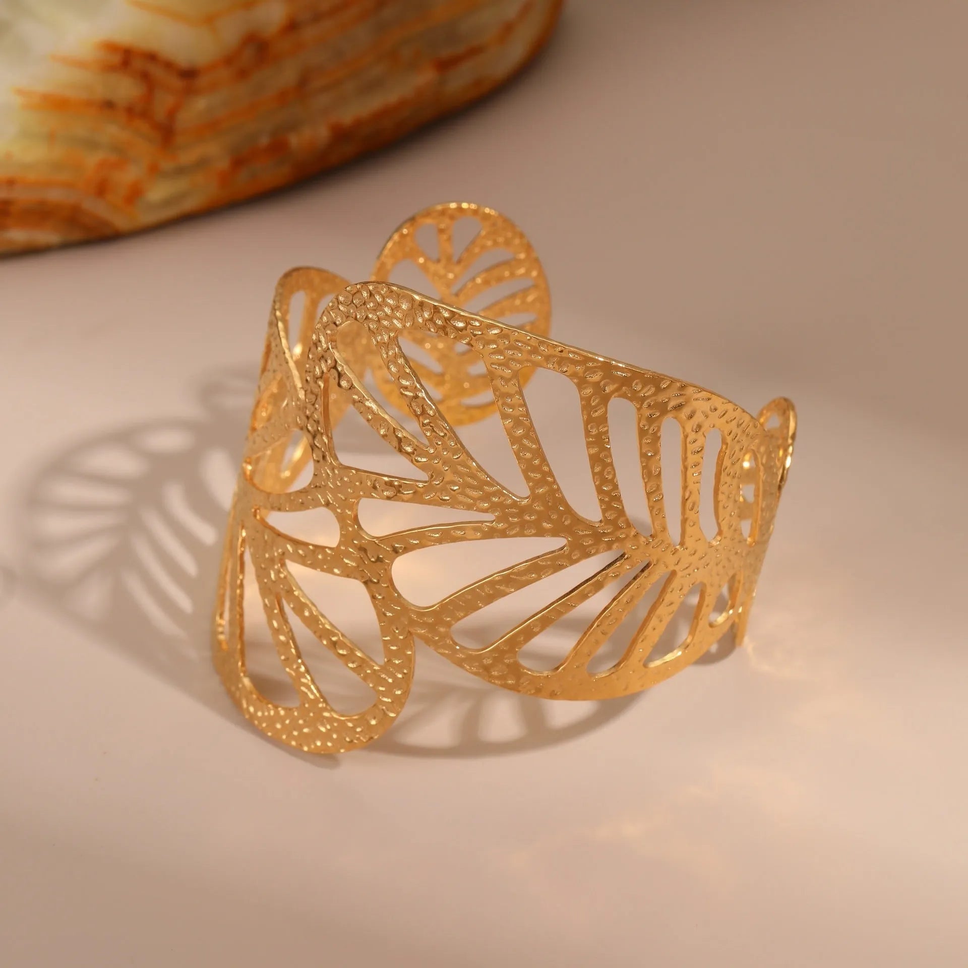 Gold stainless steel wristband with geometric leaf bow design on white background