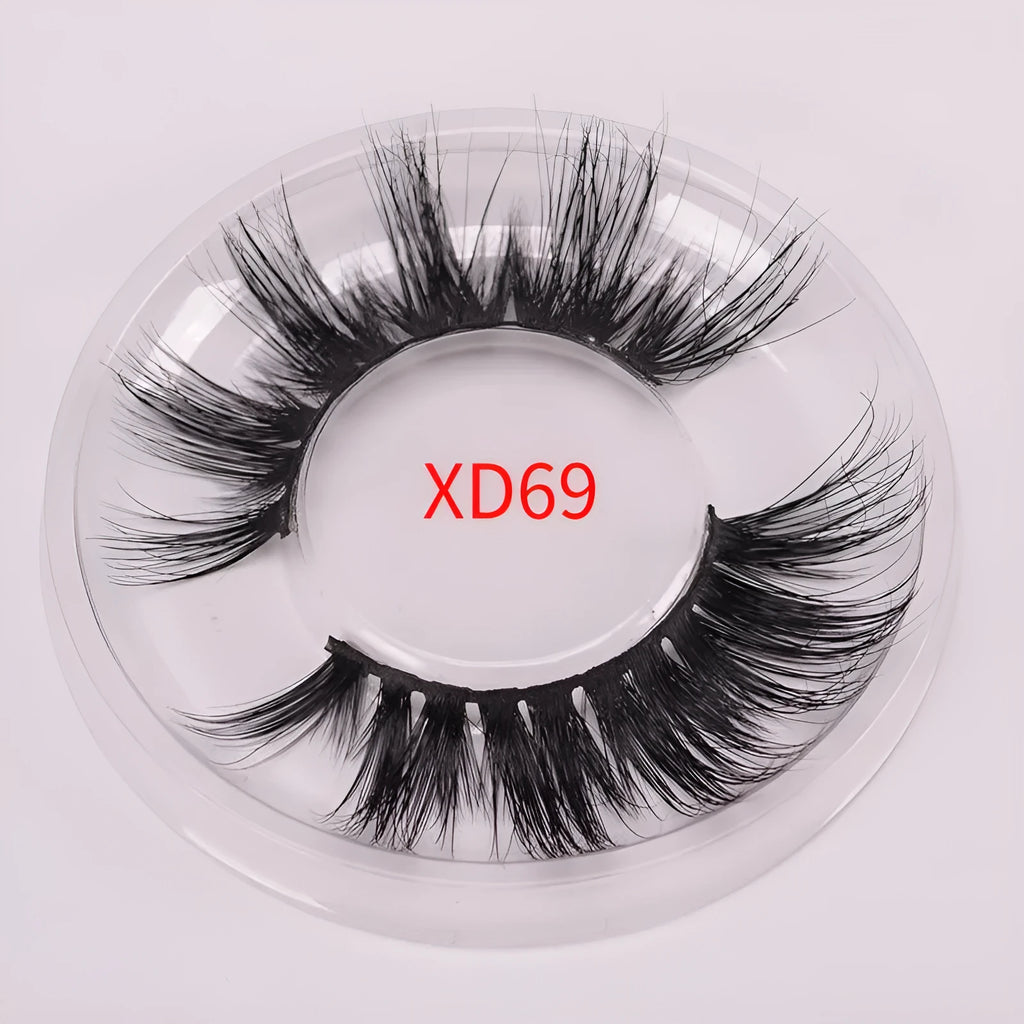 A pair of handmade 5D false eyelashes made from mink hair, shown with a double-headed brush and a hair cap.