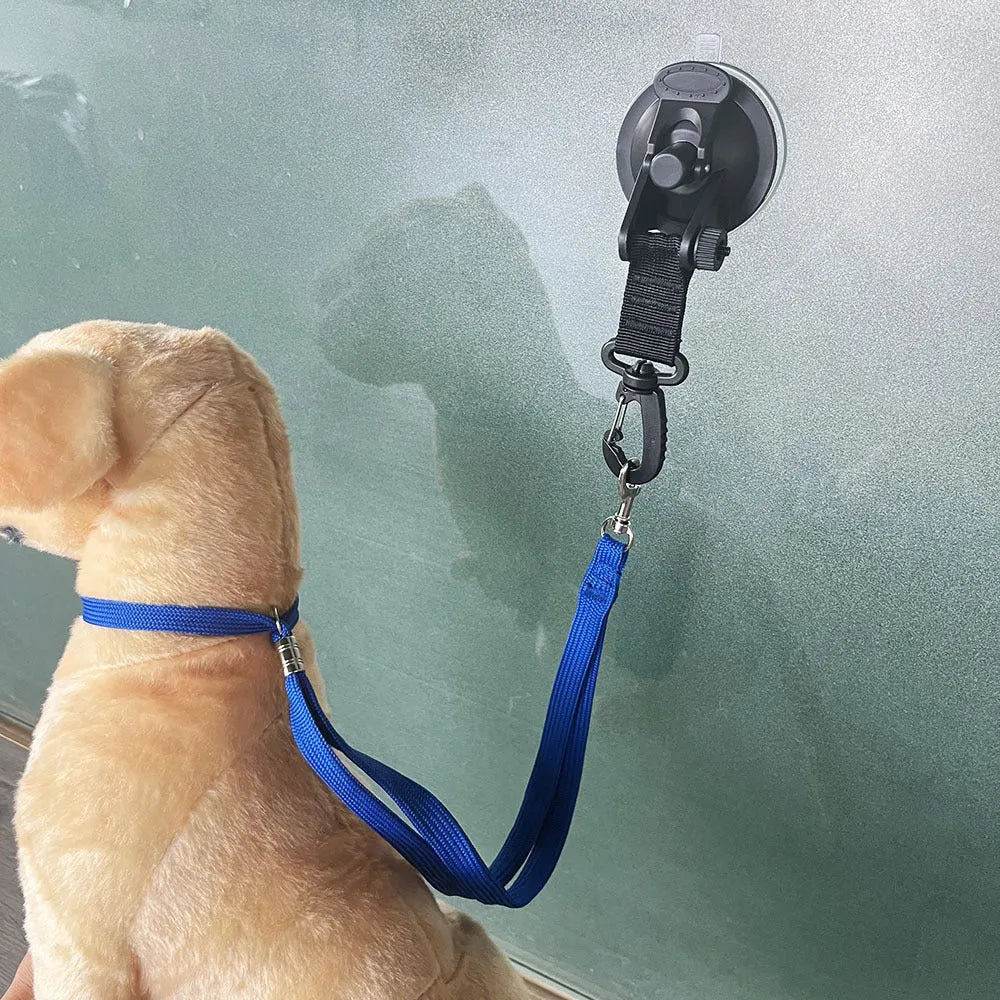 Pet bathing restraint tool with large suction cups, handcuffs, and a connecting rope on a bathroom tile background.