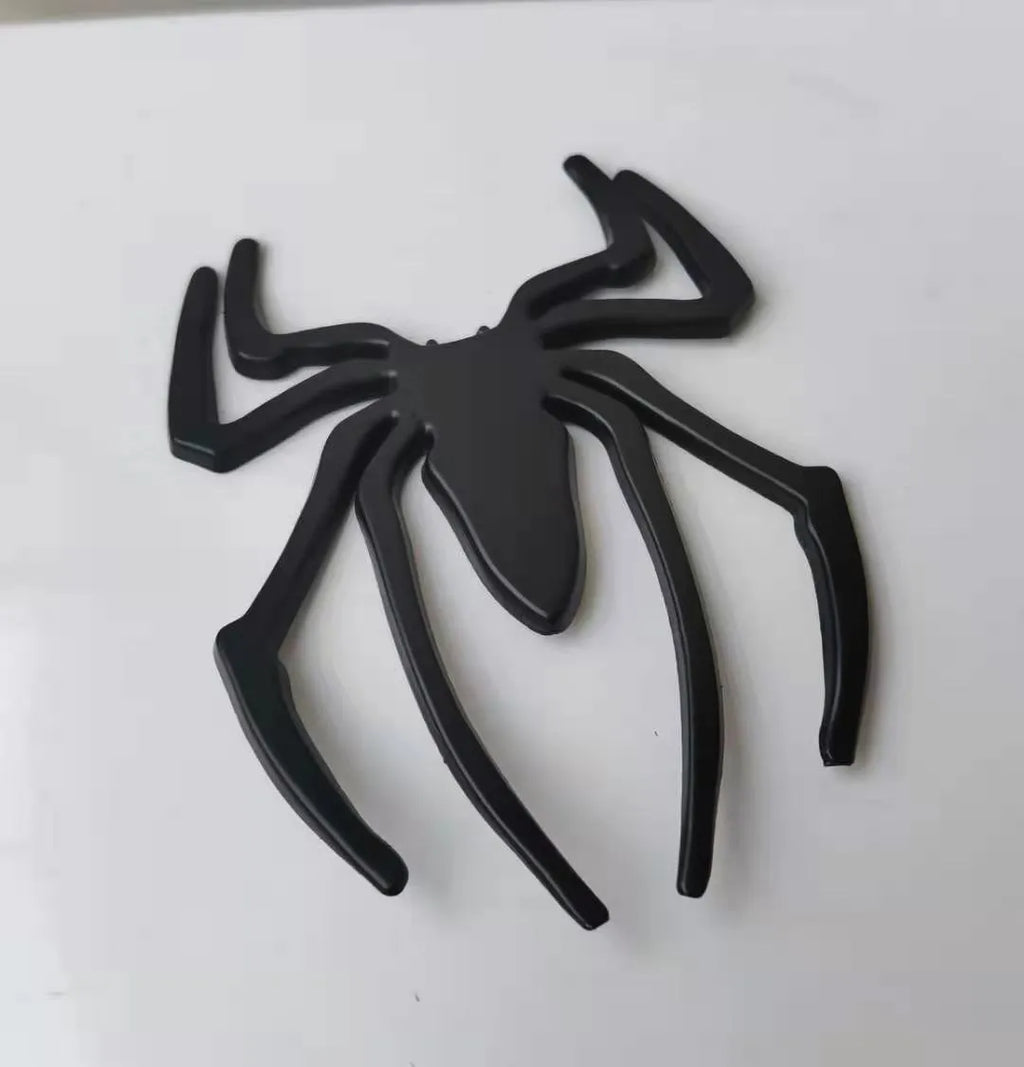 Three-dimensional metal spider bumper sticker in zinc alloy, shown in gold colour.