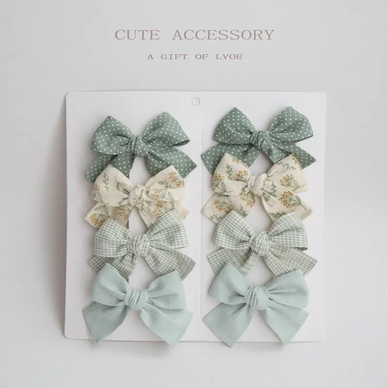 Set of eight fabric hairclips with dovetail bows in a chosen colour like beige grid dots or pink.