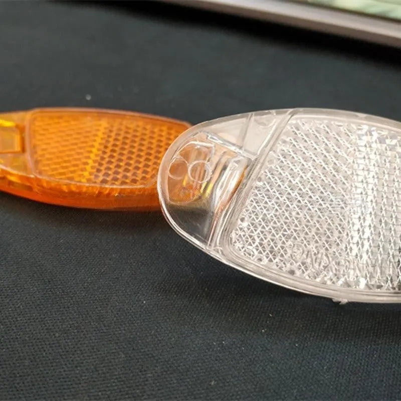 White and yellow plastic bicycle spoke reflector measuring 7.2cm by 3.5cm for night cycling safety