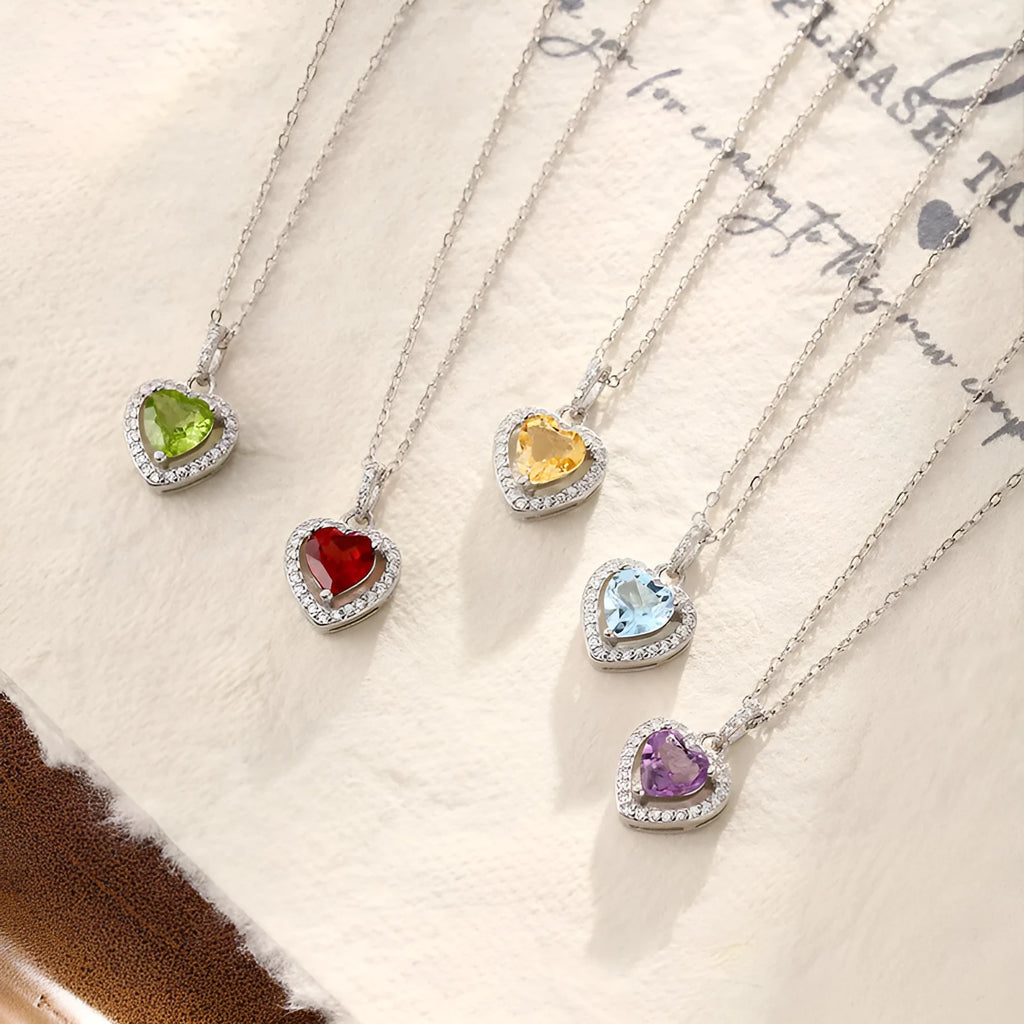 Close-up of a sterling silver heart necklace with an inlaid amethyst gemstone on a cross chain.