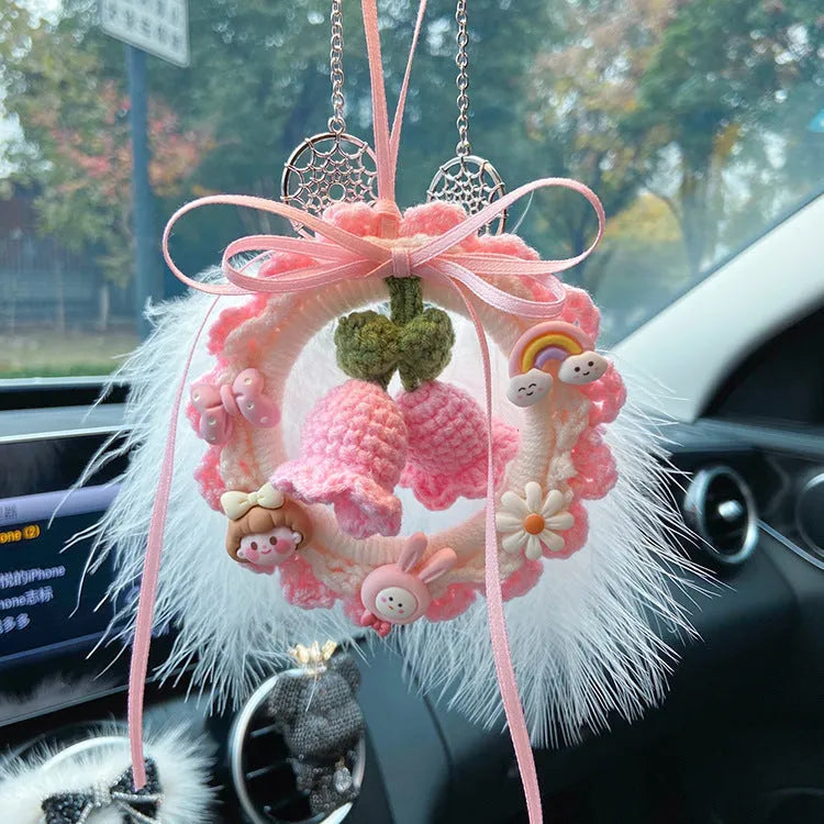 Handmade woven wool bell orchid car pendant on a green background, showing textured detail.