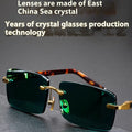 Dark green frameless crystal sunglasses with a glasses case and cleaning cloth.