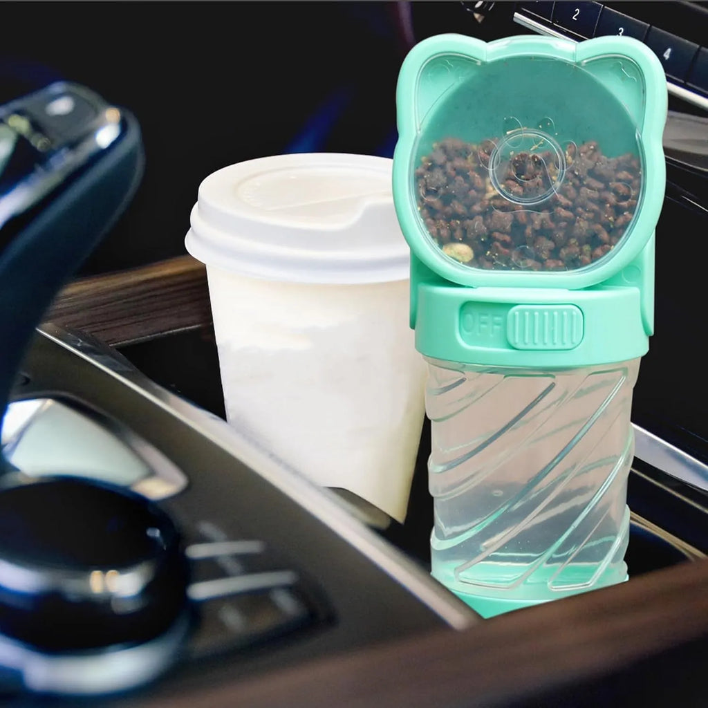 Green 3-in-1 pet water bottle with food container top and waste bag dispenser base, held by hand strap.