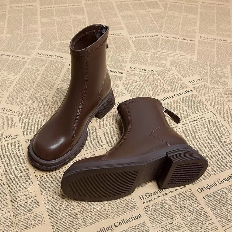 Women's black flat-heel ankle boot with back zipper and round toe on a neutral background.