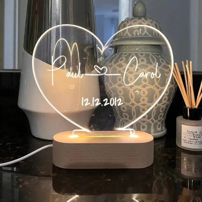 Custom transparent acrylic night light with engraved names and date, lit by LED base.
