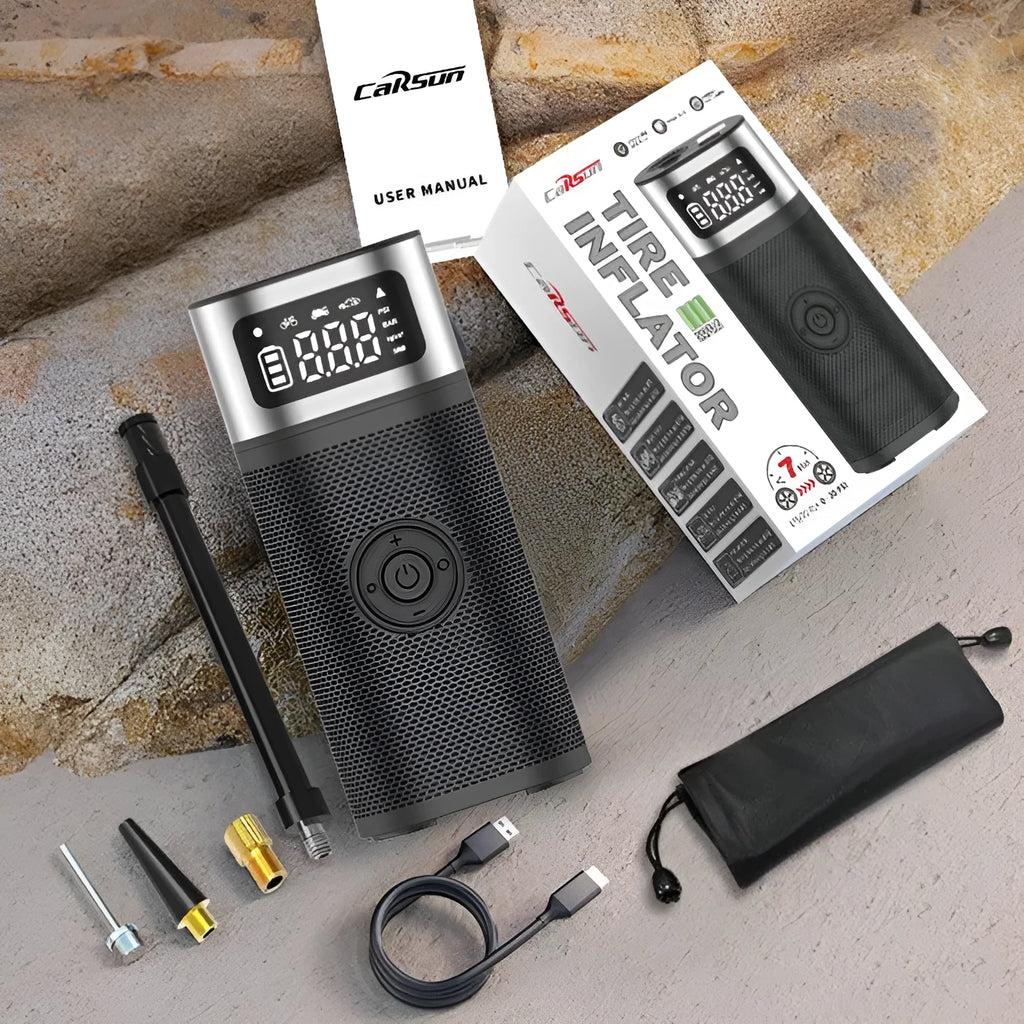 Black portable wireless smart air pump with display, charging cable and nozzle attachments on a dark surface.