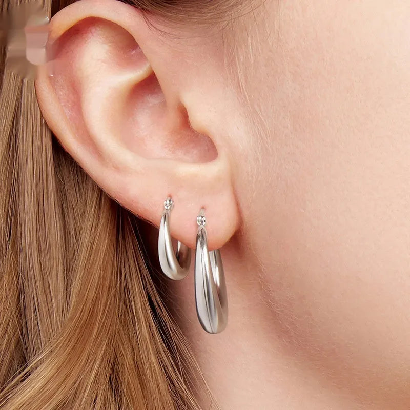 A pair of copper ring-shaped ear clip earrings with silver posts on a white background.