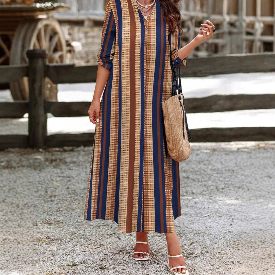 Camel-coloured women's long dress with vertical stripes, V-neck collar, and long sleeves on a mannequin.