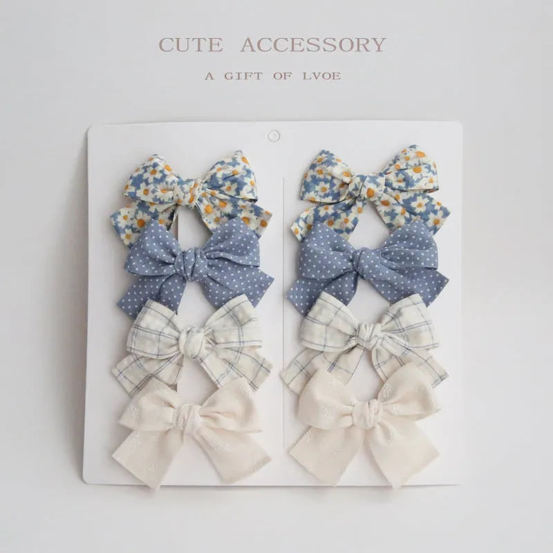 Set of eight fabric hairclips with dovetail bows in a chosen colour like beige grid dots or pink.