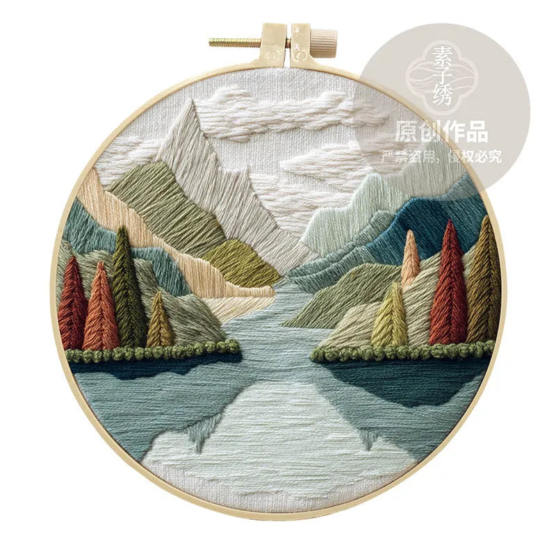 DIY embroidery kit with landscape-printed cotton fabric, embroidery hoop, needles, and coloured thread spools.